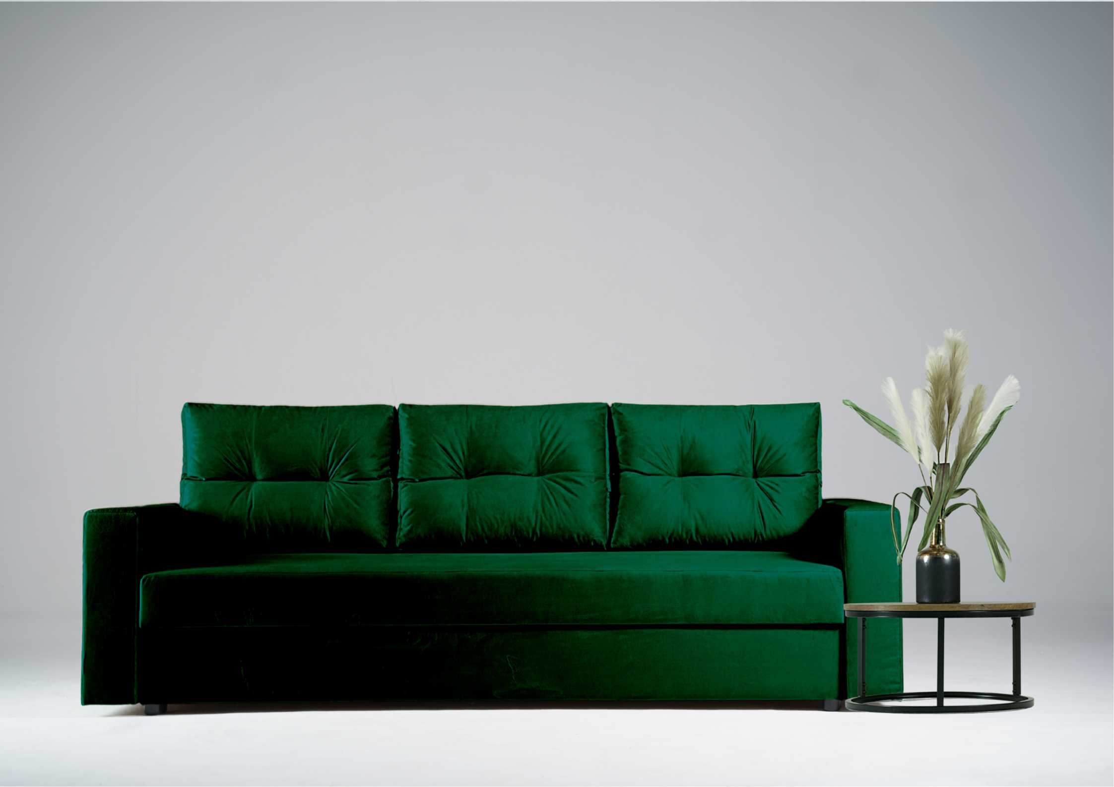 Zielona kanapa z pikowanymi poduszkami